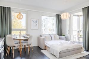 a white living room with a bed and a table at Calm Suite with Sauna and Free Garage - Heart of Lapland in Rovaniemi