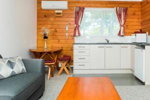 cocina y sala de estar con sofá y mesa en Tudor Park Motel en Gisborne