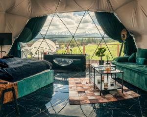 a room with a bed and a couch and a table at Góralski Harem Osada Glamp & Glass z Jacuzzi i Balią in Zakopane