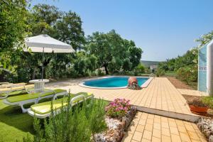 un patio trasero con piscina con sillas y sombrilla en Casa Alcaria, en Alcaria
