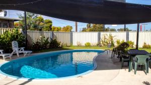a swimming pool in a backyard with a table and chairs at Wangaratta Motor Inn in Wangaratta