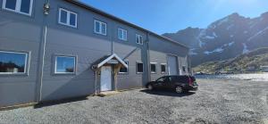 レーヌにあるReine Brygga Apartmentsの山を背景にした建物の隣に停車する車