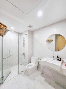 a white bathroom with a toilet and a sink at TMS Quy Nhơn - RUBY Luxury Apartment in Quy Nhon