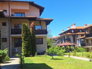 a large building with trees in a yard at Apartment Pirin in Bansko