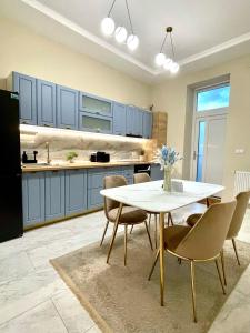a kitchen with blue cabinets and a white table and chairs at Central View Apartment in Turda