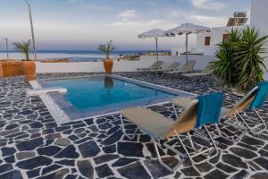 a swimming pool with chairs and an umbrella at Ciel Blue Villas with Private Pools in Kiotari