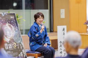 a woman sitting on a chair holding a microphone at KAMENOI HOTEL Akita Yuze in Kazuno