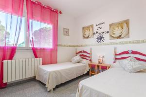 two beds in a room with pink curtains and a window at Villa Sol in La Canyera