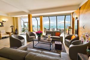 a living room with couches and tables and windows at Family Golf Hotel in Royan