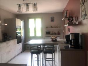 une cuisine avec un comptoir et deux tabourets de bar dans l'établissement VILLA AVEC PISCINE, à Roussillon