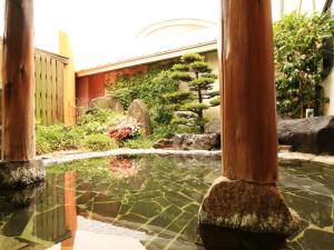 un jardín con un estanque en un edificio en Ryokan Kamomeso en Sado