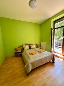 a bedroom with green walls and a bed with two towels at Heviz Gracia Apartment in Hévíz