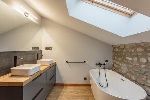 un bagno con ampia vasca bianca e lavandino di Domaine Le Pehau 8 - Avec jardin et terrasse a Osserain-Rivareyte