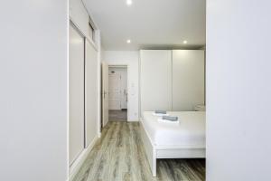 Cette chambre blanche comprend un lit et un miroir. dans l'établissement Casa Baleeira - Modern apartment with Seaview, à Armação de Pêra