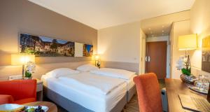 a hotel room with a large bed and a desk at PLAZA INN Goslar in Goslar