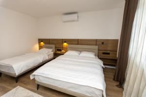 two beds in a hotel room with white sheets at Villa Hanna Ilidža in Kamenjača +43 photos