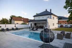 a swimming pool with chairs and a house at Villa Hanna Ilidža in Kamenjača
