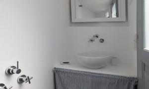 a white bathroom with a sink and a mirror at Koukios Cell in Serifos Chora +7 photos