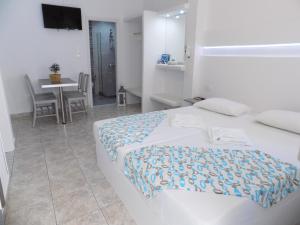 a white bedroom with a bed and a table and a tableablish at Anemos Studios in Adamantas