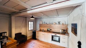 a kitchen with white cabinets and a wooden wall at Fachwerkhaus Hufschmiede - Blauer Salon in Zirndorf +11 photos