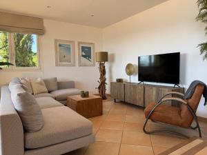 Una sala de estar con un sofá y un televisor de pantalla plana. en La Villa Belvédère, en Le Lavandou
