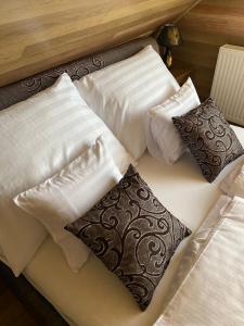 a bed with three pillows on top of it at LORD LUX Apartmanok in Hajdúnánás