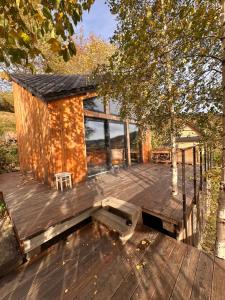 eine Holzterrasse mit einer Hütte und einem Stuhl darauf in der Unterkunft OFFowka in Przyborów