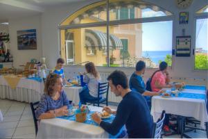 a group of people sitting at tables in a restaurant at Hotel Deutsche Familien in Finale Ligure