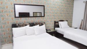 two beds in a hotel room with a mirror at Hotel Silver Sand Multan in Multan