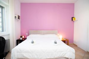 a bedroom with a white bed with a purple wall at Moderna villa con piscina a due Passi dal Golf Club in Pavona +25 photos
