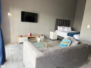 una sala de estar con un sofá y una cama en Dainfern Fourways apartment offering privacy and a lavishly expansive balcony views, en Sandton