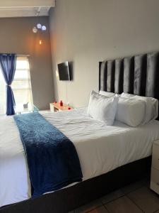 Un dormitorio con una cama grande con una manta azul. en Dainfern Fourways apartment offering privacy and a lavishly expansive balcony views, en Sandton