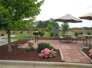 a patio with tables and an umbrella and flowers at Affordable Suites Conover / Hickory in Conover