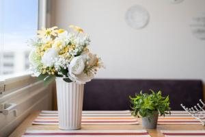 a white vase filled with flowers on a table at Stranddistel 4 Hafenkoje in Burgtiefe auf Fehmarn 