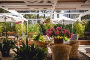 米兰马瑞提那Hotel Saraceno Resort with Private Beach的一个带桌椅、鲜花和遮阳伞的庭院