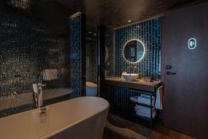 上海市にあるNeobridge Hotelの浴槽、洗面台、鏡のあるバスルーム