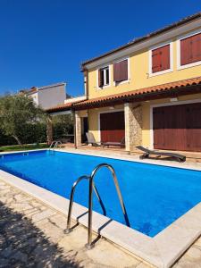 a swimming pool in front of a house at Apartment Oliva Volme in Banjole