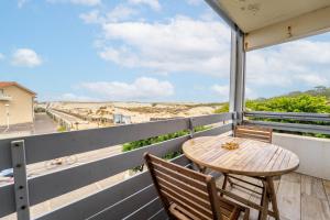 un tavolo e sedie su un balcone con vista sulla spiaggia di Appartement au pied des dunes avec vue a Biscarrosse