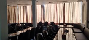 una stanza con sedie, tavoli e finestre di Ravihans Aranyam - Resort & Restaurant a Ramnagar