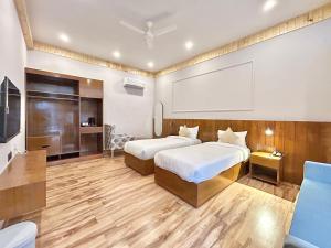 una camera d'albergo con due letti e una tv di Ravihans Aranyam - Resort & Restaurant a Ramnagar