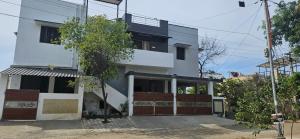 a white building with a tree in front of it at SHIs Spandha Apartments Near Coimbatore Airport in Coimbatore