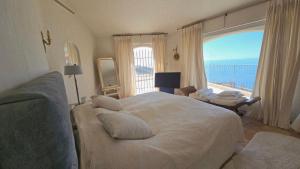 sypialnia z dużym łóżkiem i dużym oknem w obiekcie Charmante Luxusvilla vue de rêve, aussergewöhnlich großer Pool, Meerblick w mieście Théoule-sur-Mer +37 zdjęć