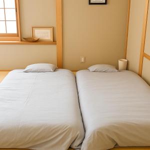 那须町森の中で仲間や家族とゆっくり過ごせる温泉付コテージ 会員制別荘地で広大なプライベート空間 ペット可 那須高原りんどうハウス的房间里有两张并排的床