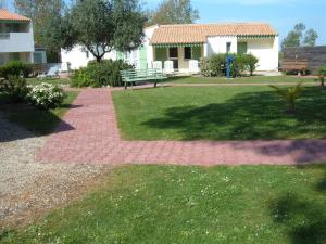 a brick walkway with a bench in a yard at Le Parasol in Ars-en-Ré