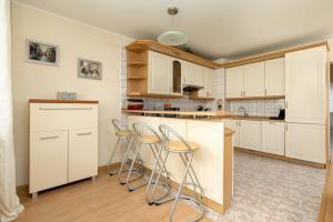 a kitchen with white cabinets and bar stools at Central Port Giełdowa Apartment by Solarento in Kołobrzeg +20 photos