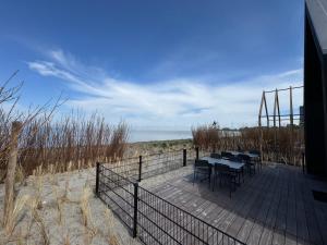 a deck with tables and chairs on the beach at Enkhuizer Strand BeachHouse Deck Acht mit Zaun Nr 408 in Enkhuizen