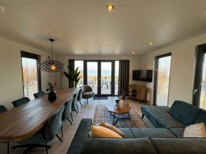 a living room with a long table and a couch at Enkhuizer Strand BeachHouse Deck Acht mit Zaun Nr 408 in Enkhuizen