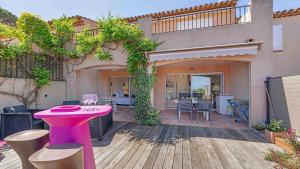 a patio with a pink table and chairs on a wooden deck at CASA SELLA Beautiful terrace with Sea View in Sainte-Maxime