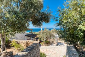 una casa con un muro de piedra y árboles en Villetta Orizzonte vista mare, en Patù
