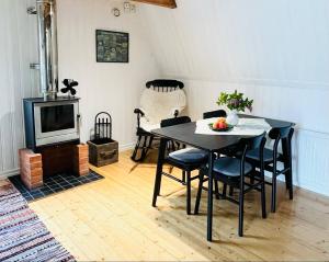 a dining room with a table and chairs and a television at Gårdshuset i Kråkerum! in JÃ¤mjÃ¶